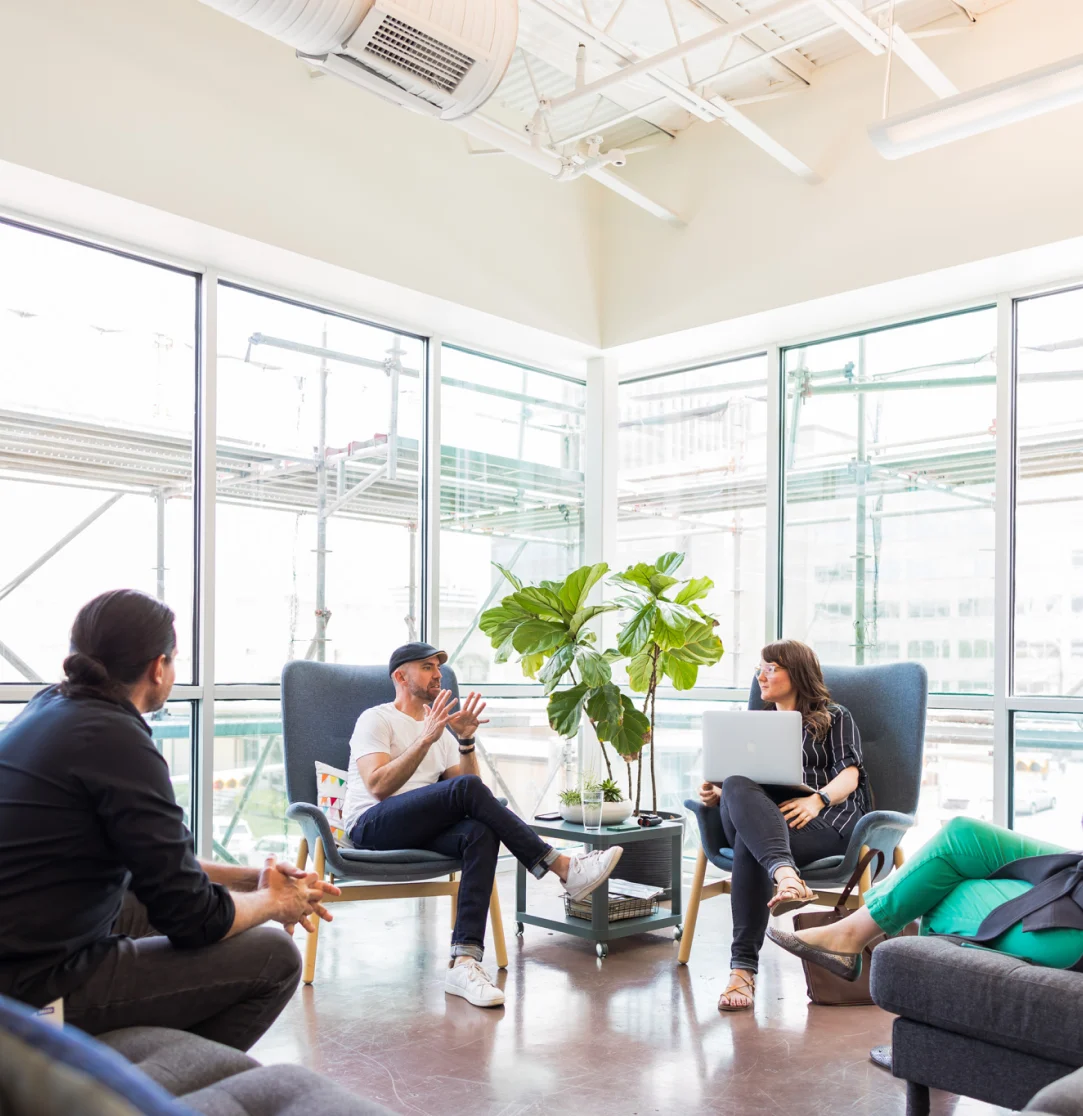4 individuals sitting down, conversing in an office common space